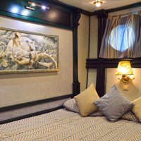 cabin interior with lights, bed, pillows, curtains and painting