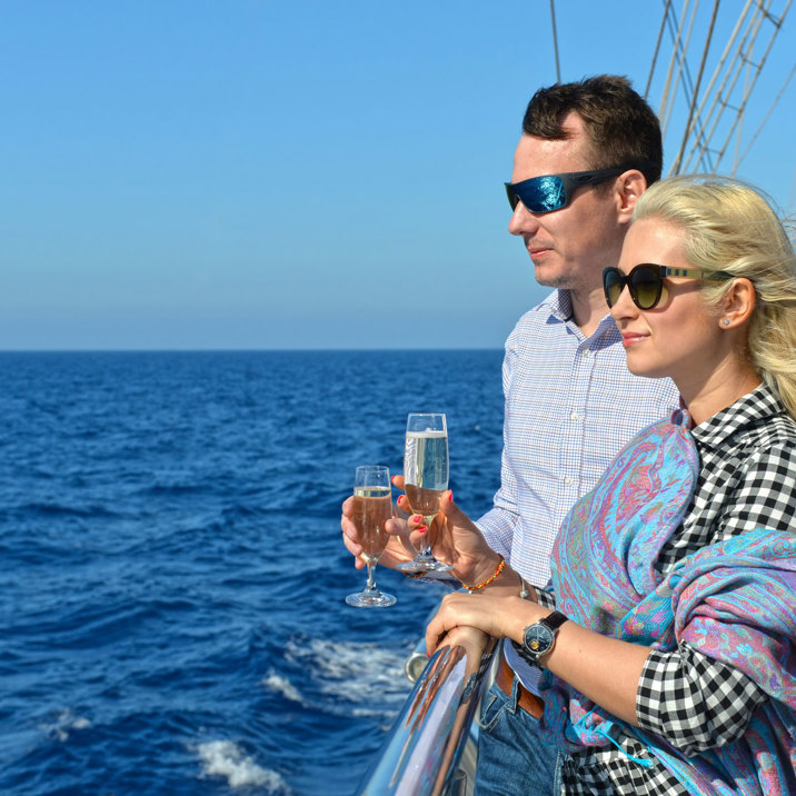 guests on the ship looking at sea holding champaigne glasses