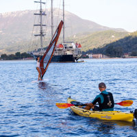 windsurf and kayak in front of the ship next to island