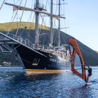guest on windsurf next to ship next to island