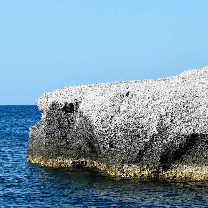 ship near low coast rocks with seagulls on top