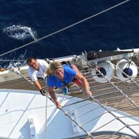 guest climbing up mast with crew 