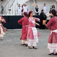traditional greek dance performers next to ship