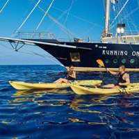 guests kayaking next to ship