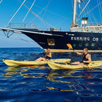 guests kayaking next to ship